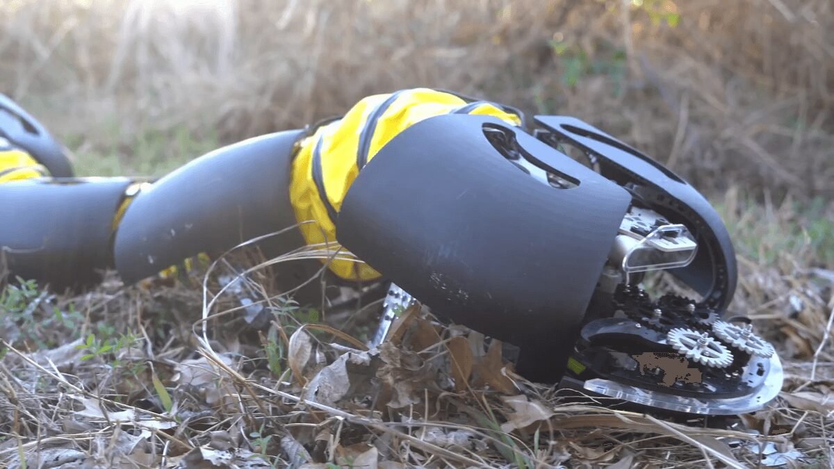 Robotic snake in grassy terrain, featuring gears and yellow accents.