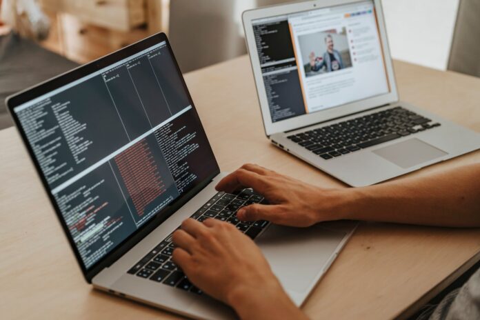 A developer coding on a laptop with code visible on the screen