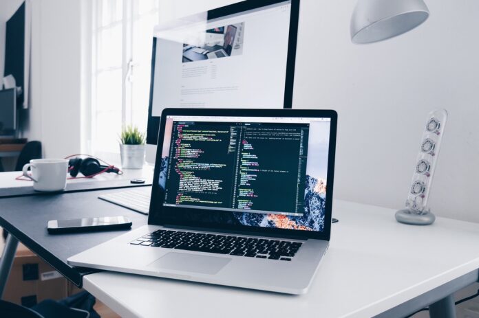 Laptop on desk showing coding interface with multiple code windows open